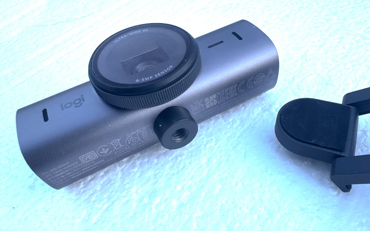 Веб-камера Logitech с большим объективом и съемным зажимом, опирающаяся на текстурированную поверхность.