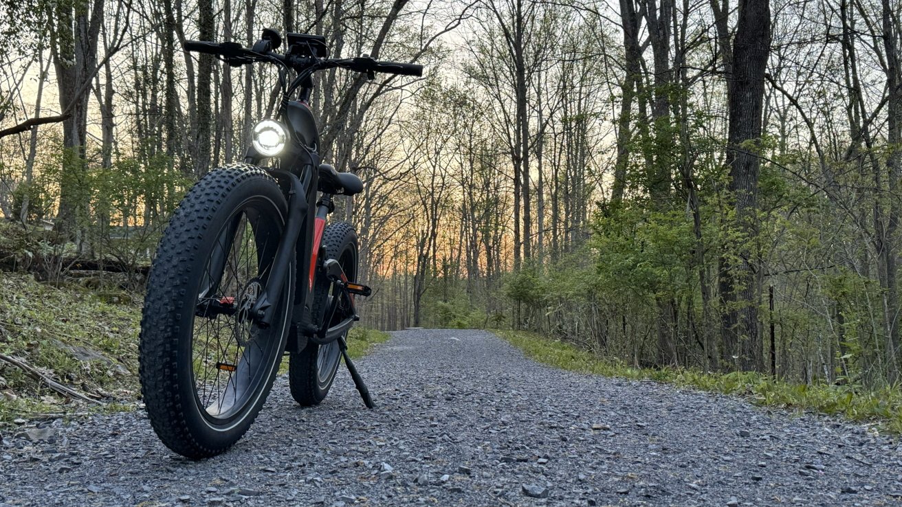 Heybike Hero на трассе на закате, с включенными фарами.  Толстые шины заметны под низким углом.