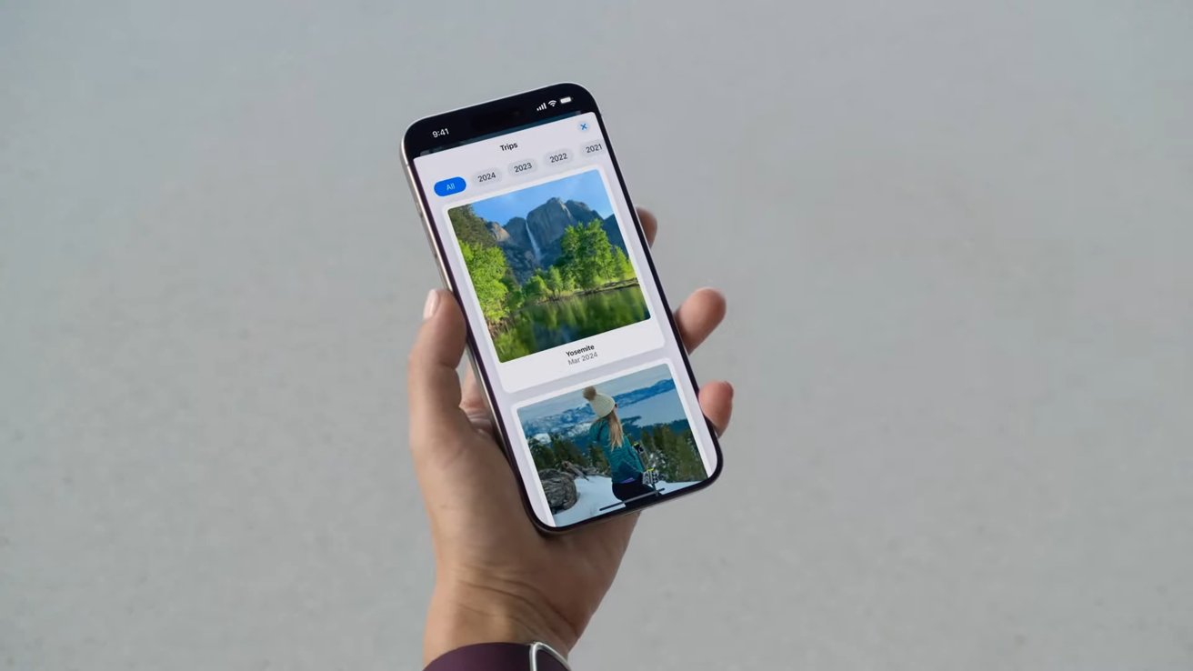 Рука держит смартфон, на котором отображаются фотографии поездки, а на запястье видны наручные часы.