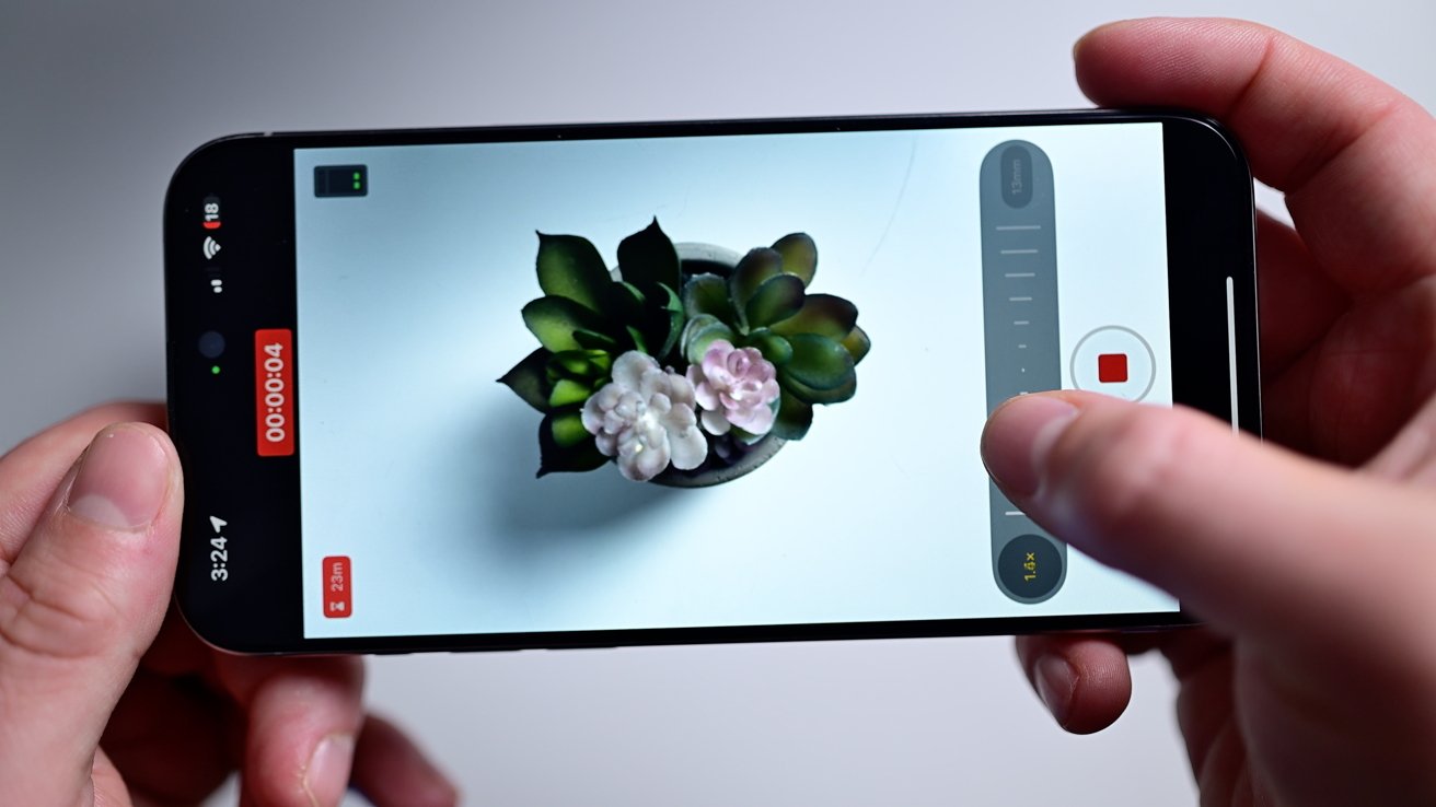 Демонстрация Final Cut Camera на iPhone, удерживаемом в горизонтальной ориентации над белым столом, с выделенным ползунком масштабирования с правой стороны