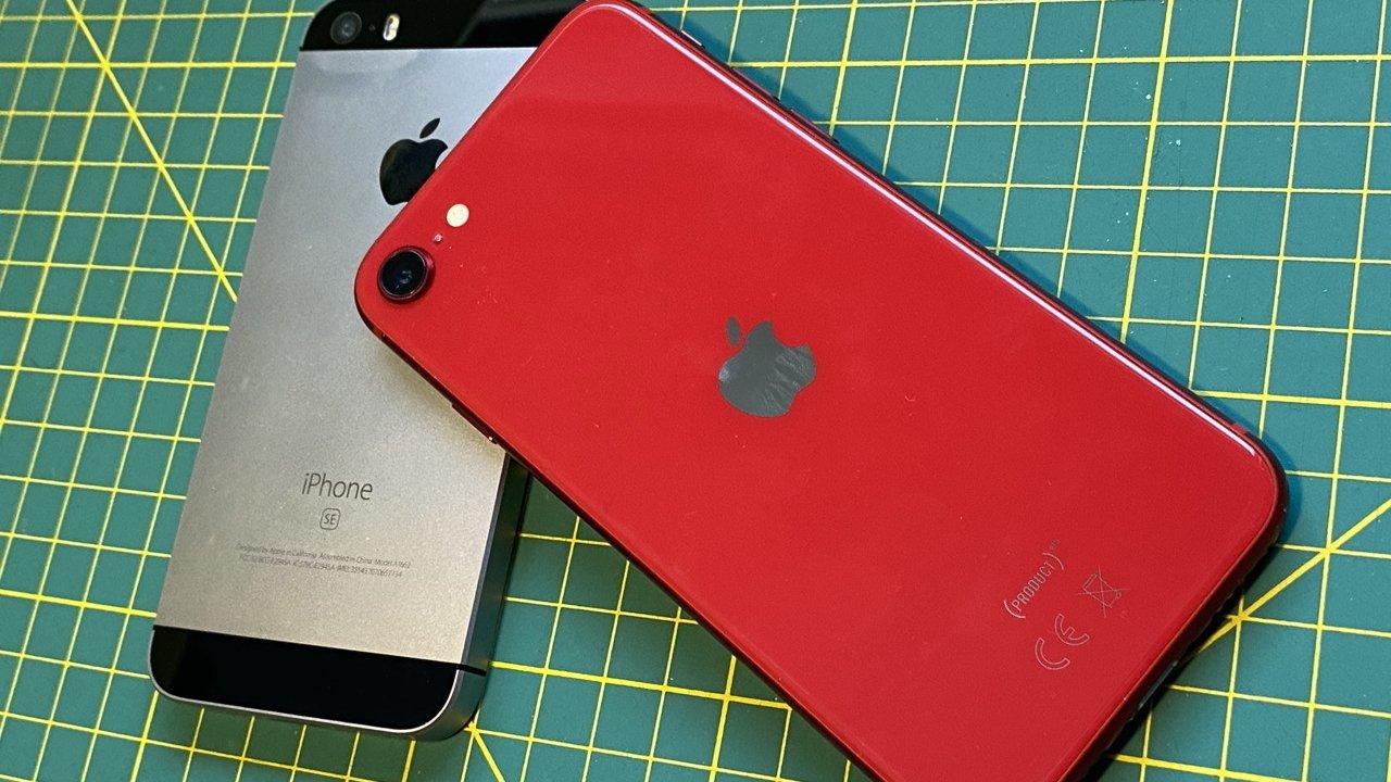 На зеленом коврике для резки лежат два iPhone: один красный, другой серебристо-черный.