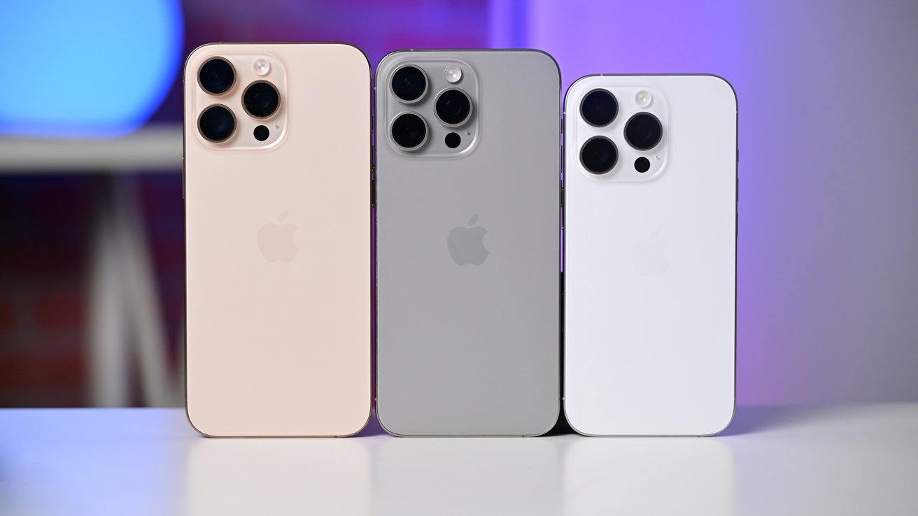 iPhone цвета пустыни, белого и натурального титана стоят на краю стола.