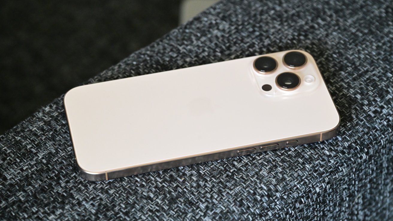 Титановый iPhone 16 Pro Max в пустыне на подлокотнике дивана