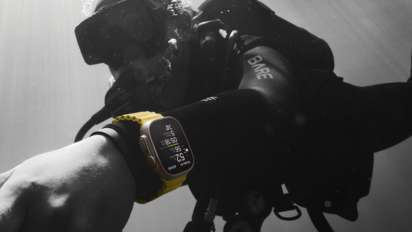 Аквалангист под водой в черном гидрокостюме и с желтыми часами Apple Watch Ultra 2, отображающими показатели погружения на запястье.