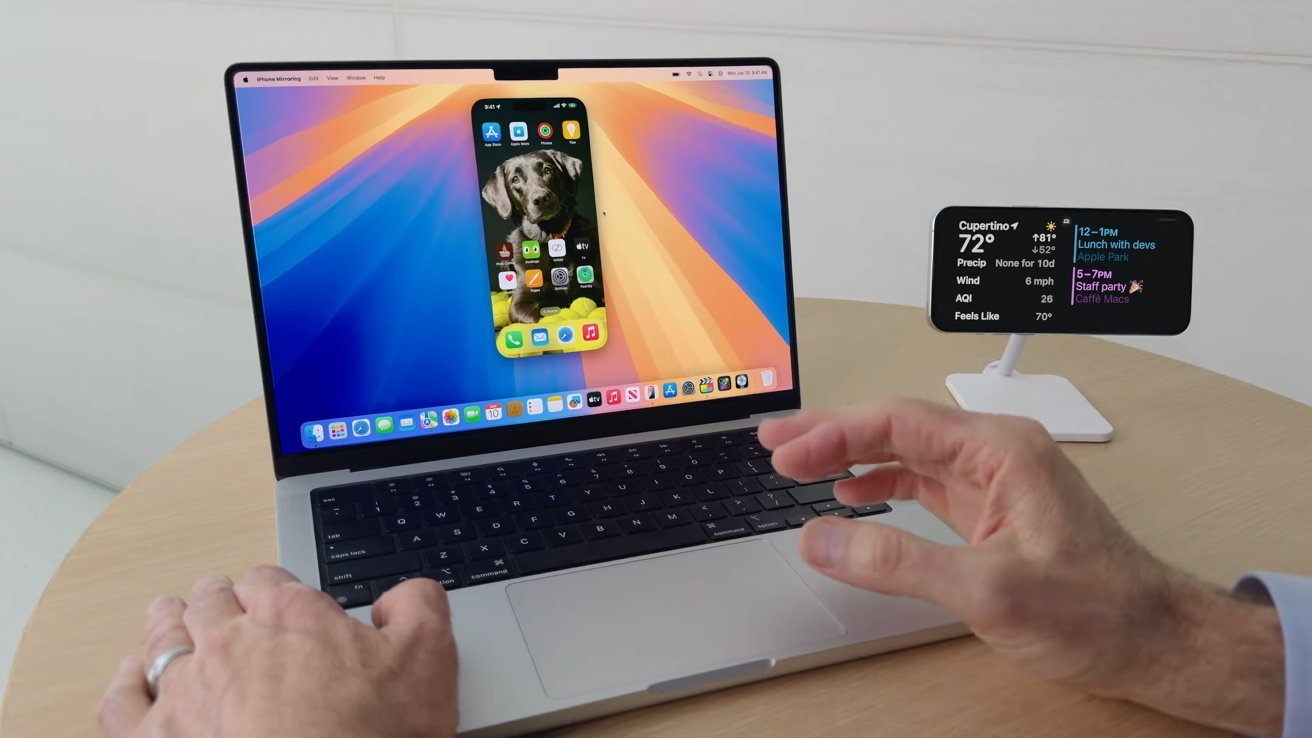 Руки печатают на ноутбуке, на дисплее которого дублируется экран iPhone, а сбоку расположен небольшой дисплей с прогнозом погоды и расписанием.