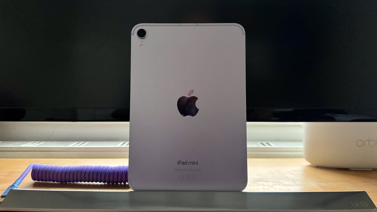 Фиолетовый iPad mini, прислоненный к монитору Samsung.