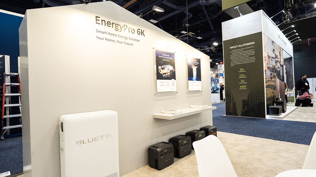На стенде Bluetti на выставке CES 2025 представлены решения для умного дома с рекламными плакатами, генераторами энергии и брошюрами на полке.