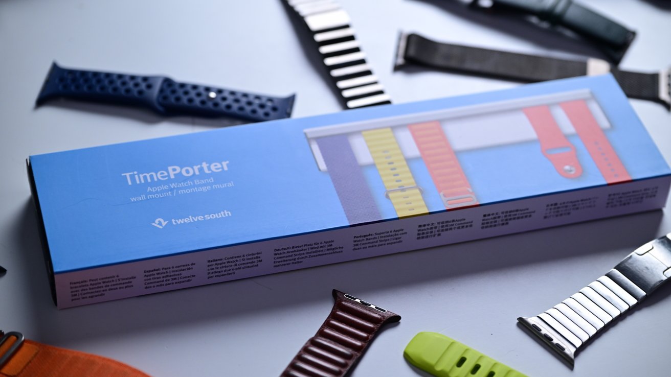 Синяя коробка TimePorter для ремешков Apple Watch в окружении разноцветных ремешков на светло-серой поверхности.