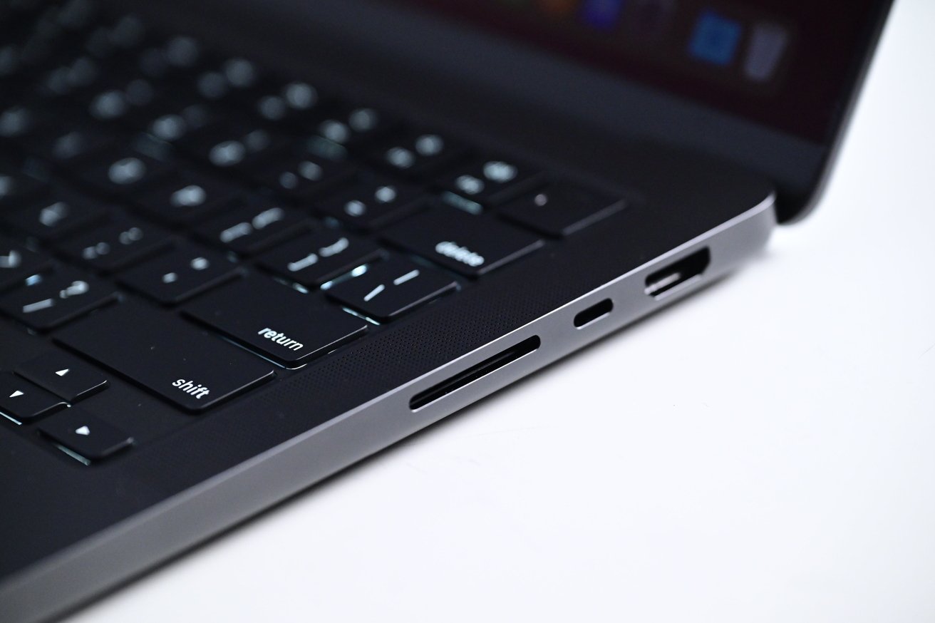 Крупный план клавиатуры MacBook Pro и боковых портов, включая USB-C и слот для карт памяти SD, на гладком черном корпусе.